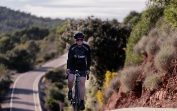 A woman cyclist trains on a road bike through a picturesque countryside landscape.